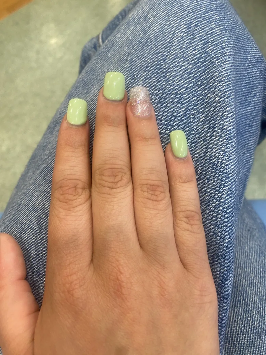 A pastel green square gel manicure with a silver glitter accent nail
