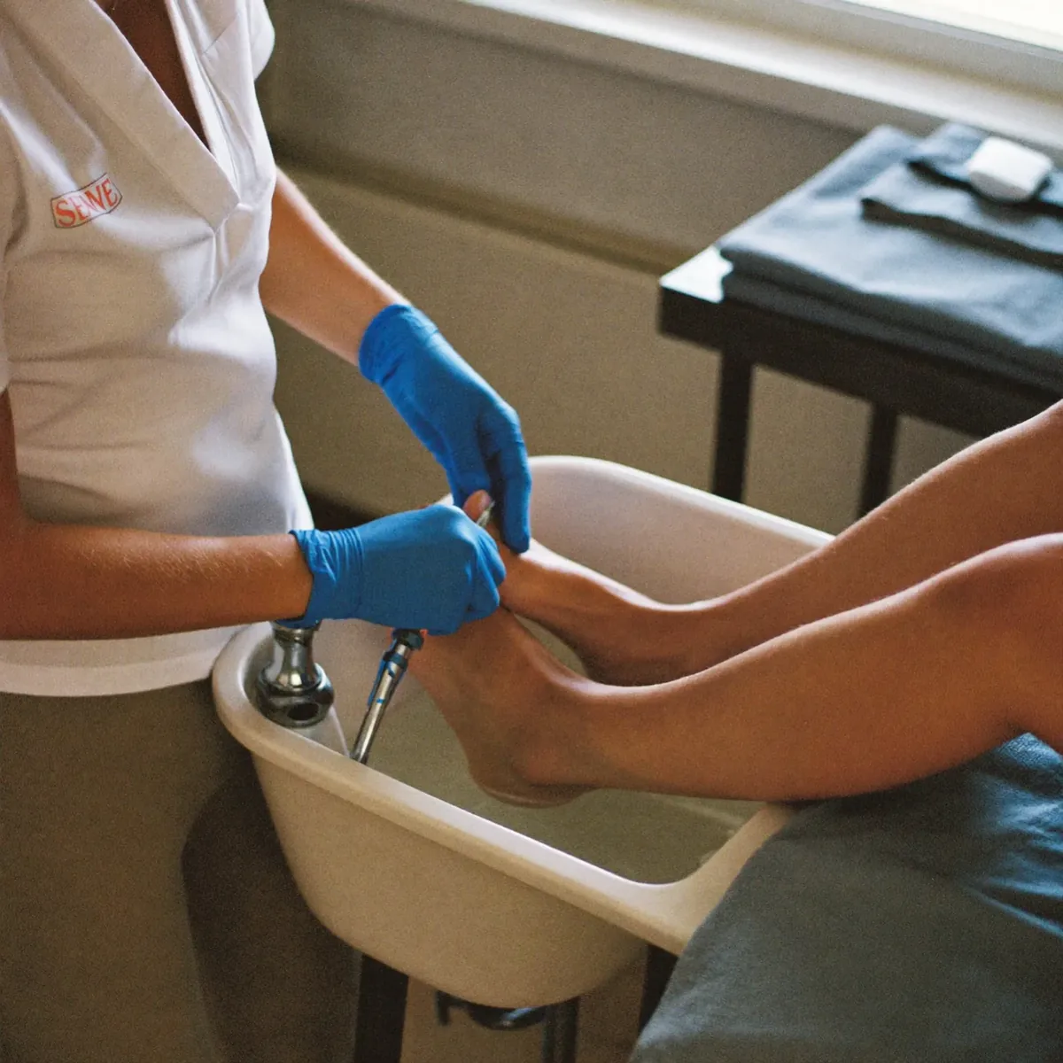 A pale blue pedicure with fine white dot detail on a light wood floor